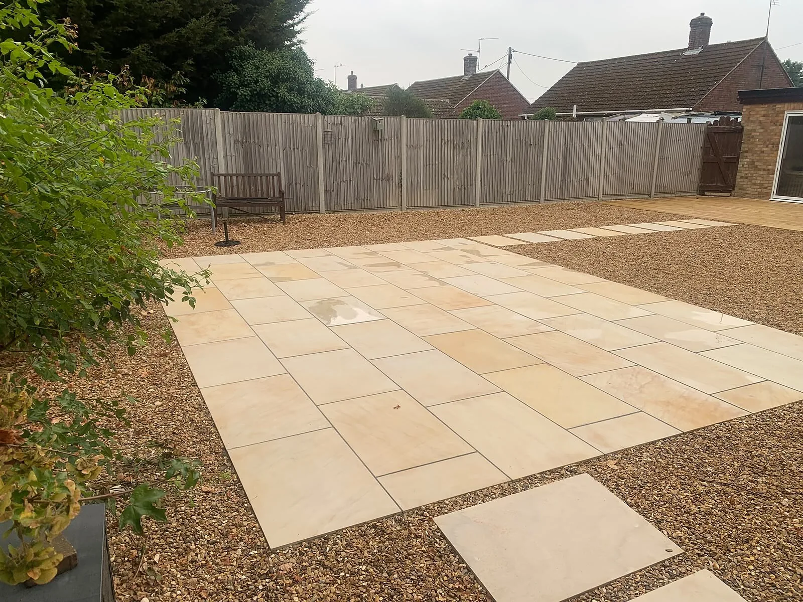Buff sandstone patio with stepping slabs across gravel in a West Norfolk garden