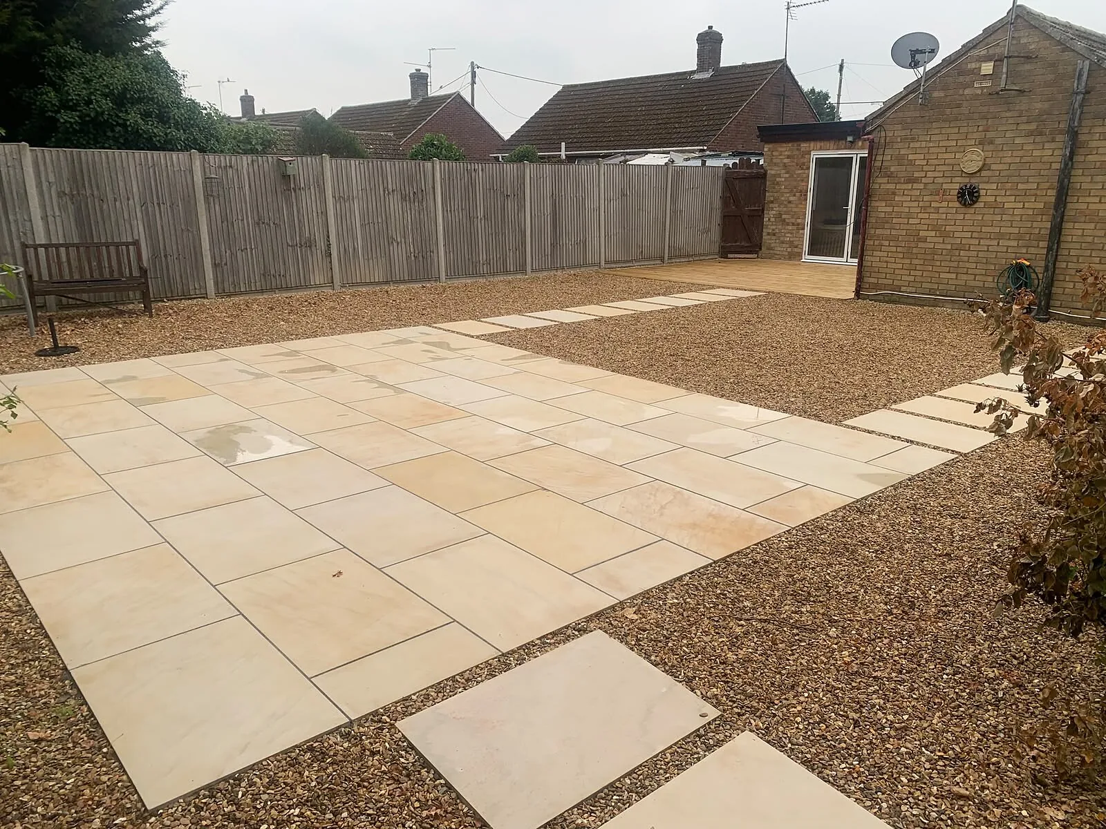 Patio with stepping slabs leading across gravel to a garden building – Fines Landscaping, West Norfolk
