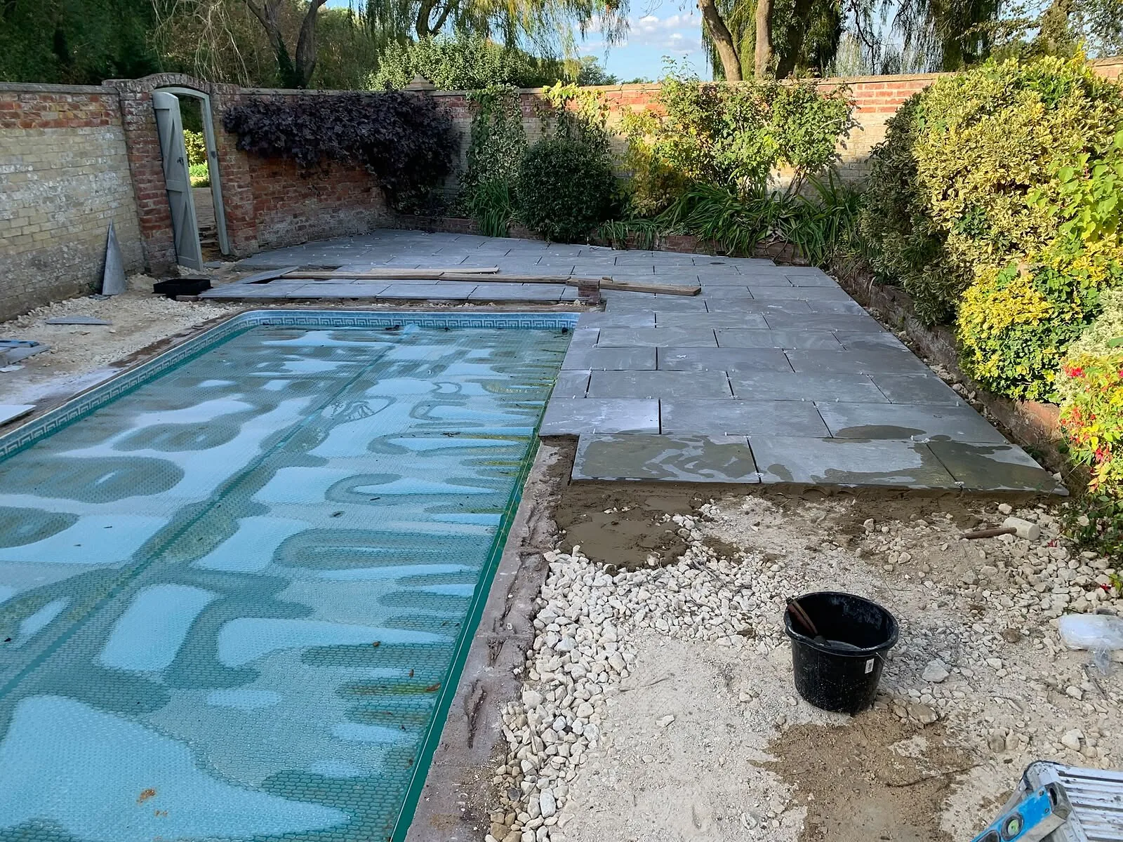 Paving being laid around a garden swimming pool – Fines Landscaping, West Norfolk