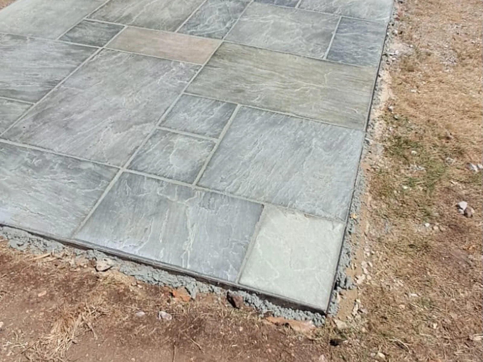 Grey paving slabs laid along the side of a house – Fines Landscaping, West Norfolk