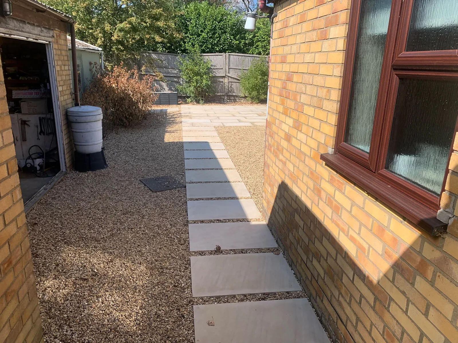 Stepping stone path set into gravel beside a brick house – Fines Landscaping, West Norfolk