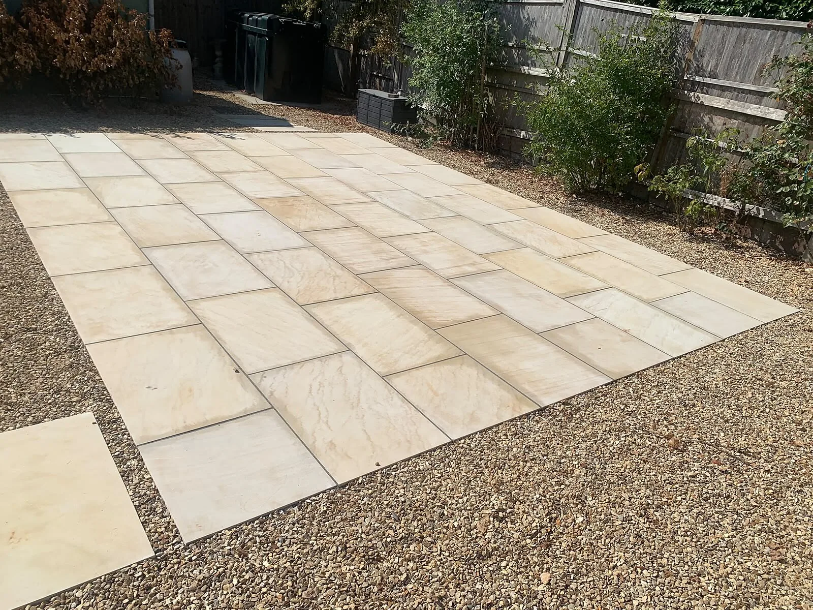 Freshly laid buff patio slabs with gravel border in a rear garden – Fines Landscaping, West Norfolk