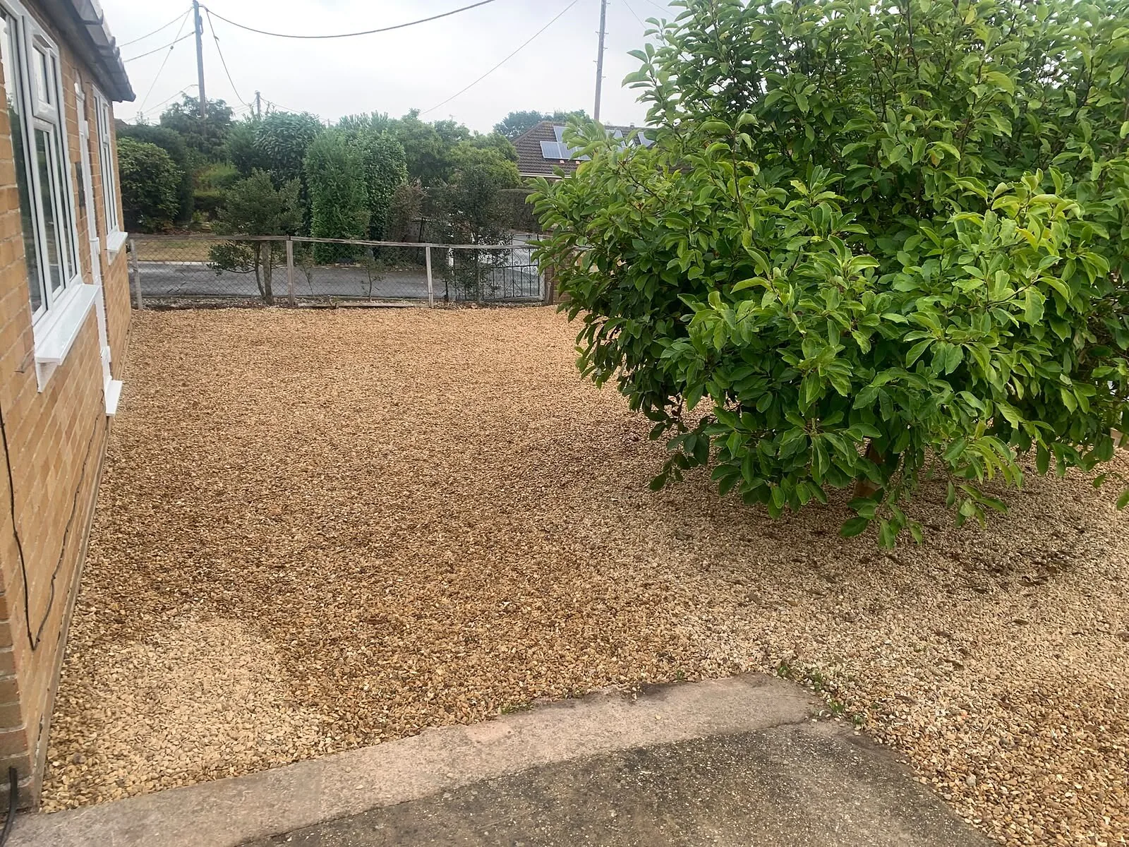New gravel garden laid beside a house and shrubs – Fines Landscaping, West Norfolk